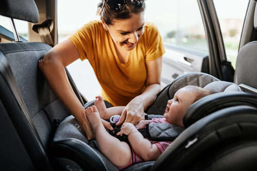 women placing baby in rear-facing carseat