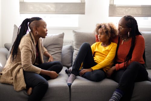 Parents sit with child on couch in conversation