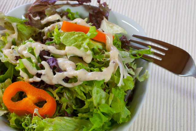 A healthy salad with dressing on it.