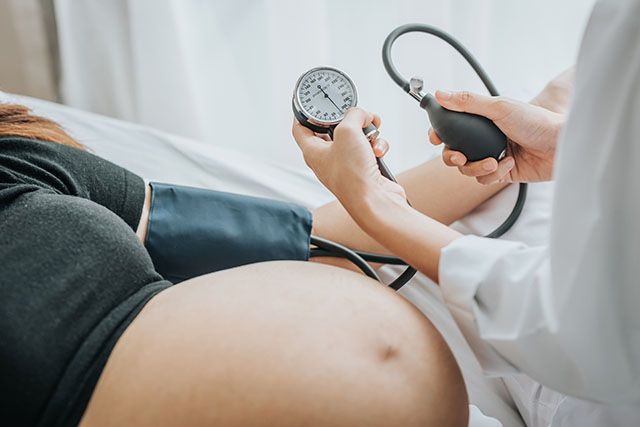doctor testing pregnant woman's blood pressure