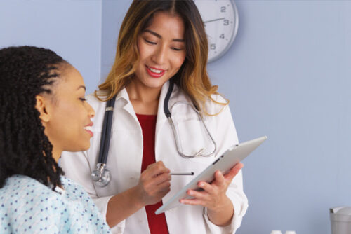 A doctor talking to their patient about what to expect from a future Pap smear with a clipboard in their hand.