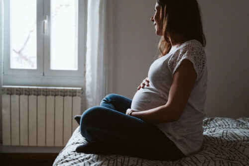 Pregnant woman sitting on bed peacefully