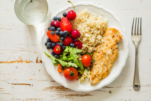 Image of a plate of food containing rice, tomatoes and fish.