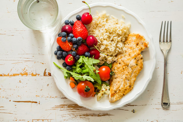 Image of a plate of food containing rice, tomatoes and fish.