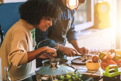 A woman cooking and eating in kitchen.