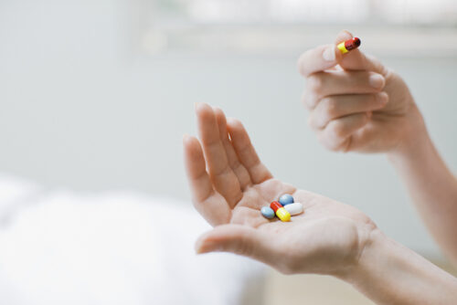 Image of a person with several multivitamins in their hand.