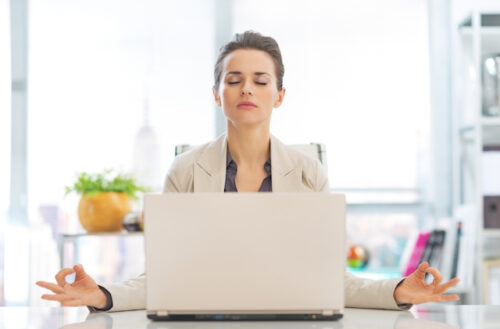 A person watching a meditating video on their laptop while meditating.