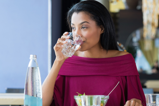 A person hydrating while drinking a glass of water.
