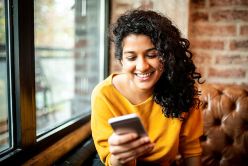 A person smiling while texting on their phone.