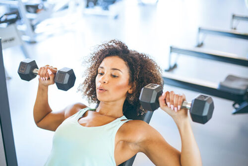 A woman lifting weights and practicing their strength training.