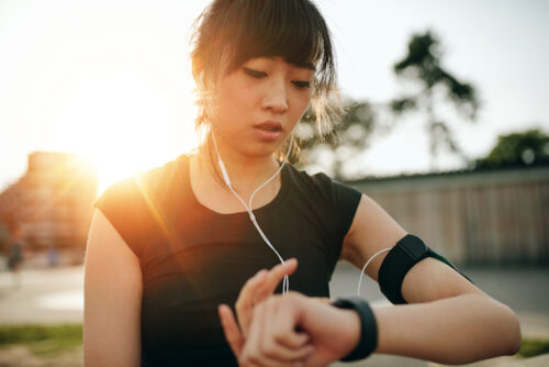A person checking their heart rate on their watch while listening to music on their headphones.