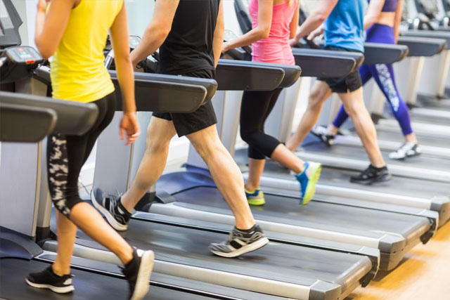 Image of the feet of several people walking on a treadmill.
