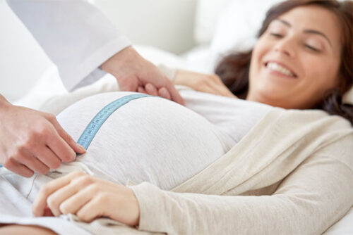 doctor measuring pregnant woman's stomach