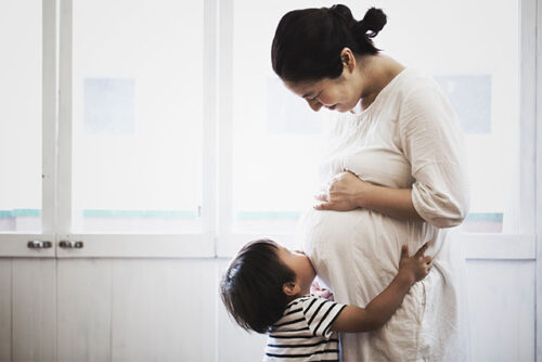 boy kissing mom's pregnant stomach