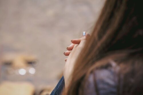 A person sitting with their hands clasped wondering where to get an abortion.