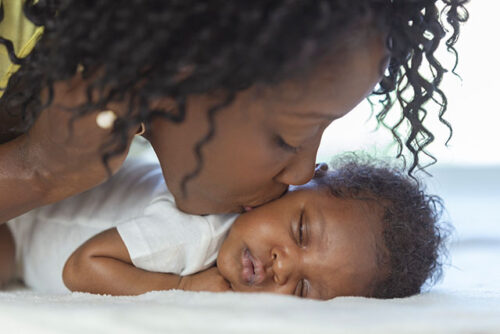mom kissing sleeping baby