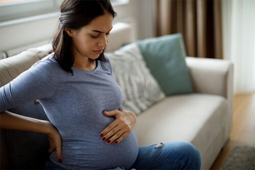 pregnant woman holding back and stomach