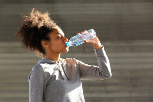 A person outside drinking from a bottle of water.