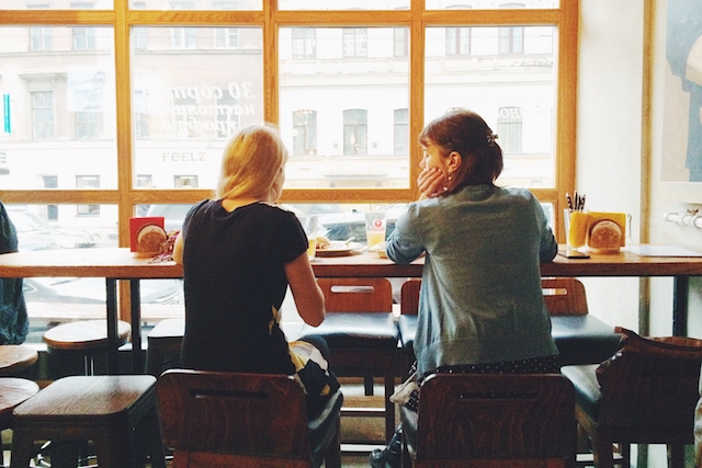 Two people sitting by a window and talking.