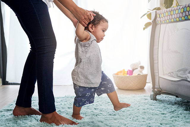 mom helping baby walk