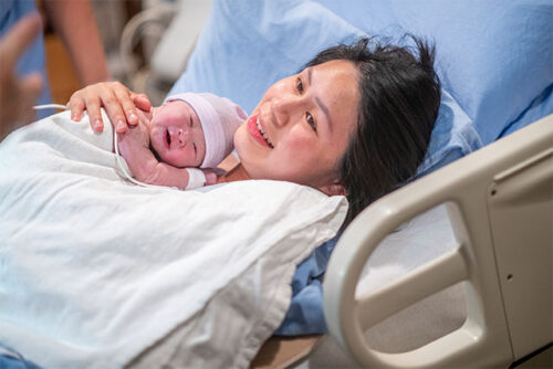 woman in hospital bed with newborn
