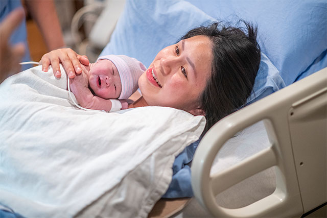 woman in hospital bed with newborn
