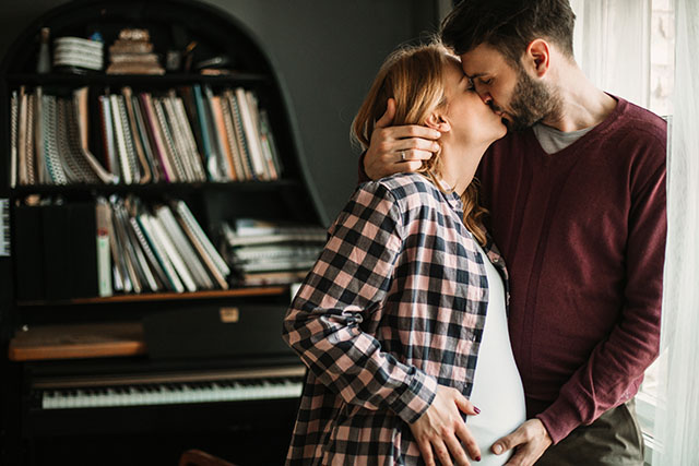 expecting couple kissing