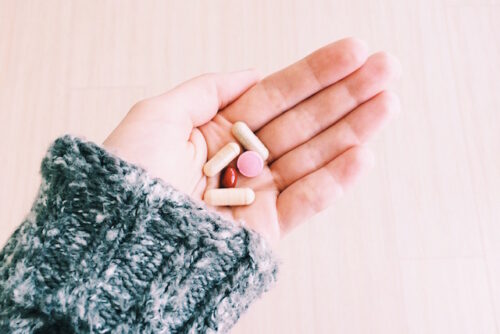 A person holding prenatal supplements in their hand.