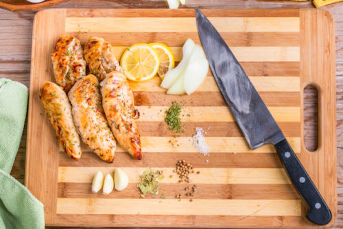 Image of chicken and vegetables chopped up next to a knife on a cutting board.