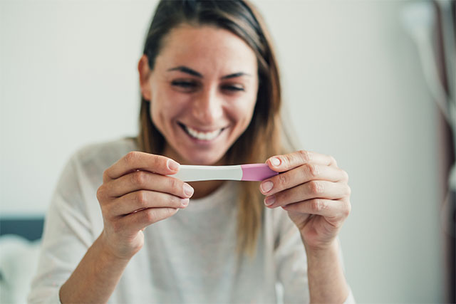woman smiling at pregnancy test