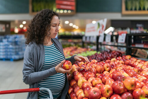 pregnant woman looking at apples