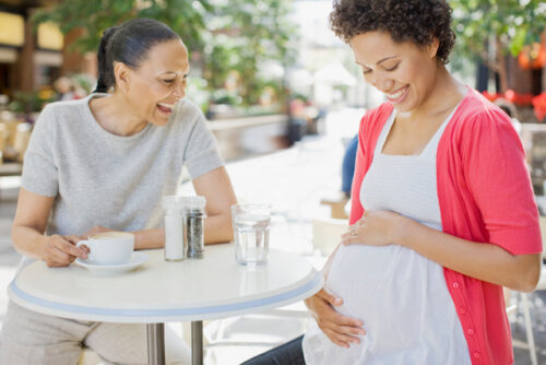 Image of one pregnant woman and her friend talking over a cup of coffee.
