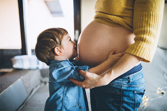 child kissing moms pregnant stomach