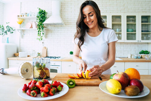 A woman cutting up fruit for her PCOS diet.