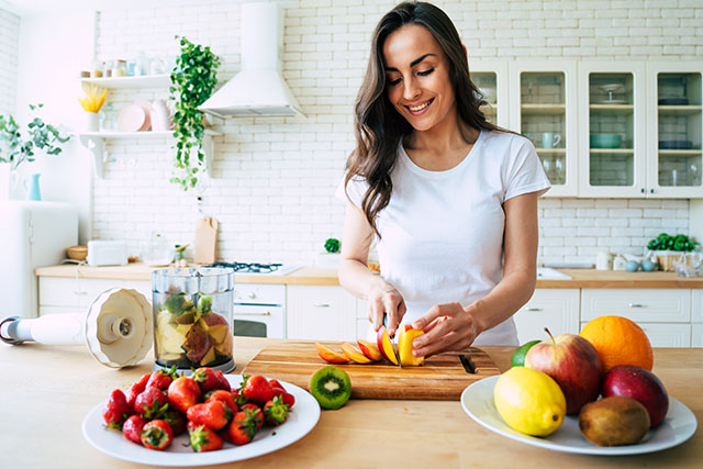 A woman cutting up fruit for her PCOS diet.