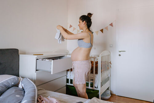 pregnant woman arranges baby clothes