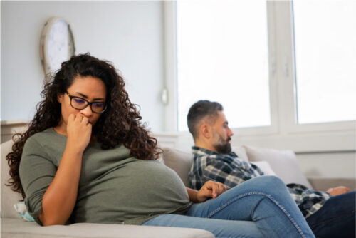 Pregnant woman on couch looking concerned