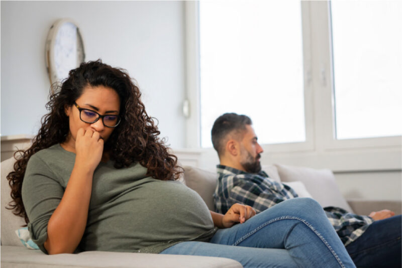 Pregnant woman on couch looking concerned