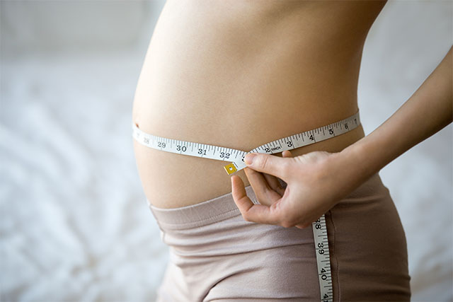 pregnant woman measuring waist