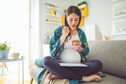 pregnant woman eating on couch