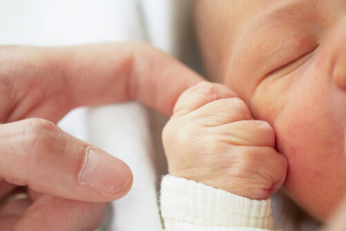 A baby grasping their parent's finger as part of their many reflexes.