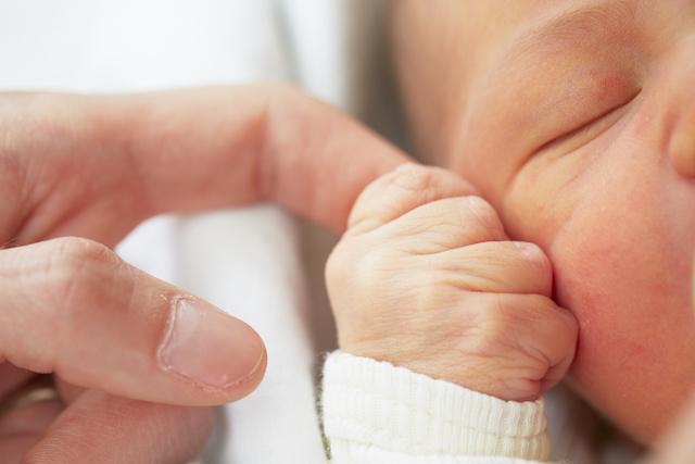 A baby grasping their parent's finger as part of their many reflexes.