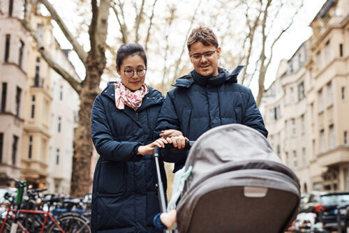 A couple traveling with their newborn in a stroller.