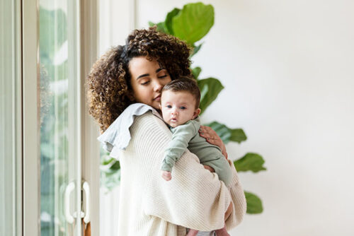 A woman burping baby to represent how to effectively burp your newborn.