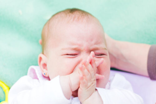A person looking at their crying baby wondering 'how long should I let my baby cry it out?'