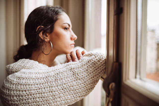 A person looking out a window and wondering how to manage depression