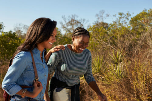 Two people walking together, one has their hand on the other's shoulder providing a form of mental health support.