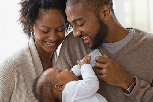 parents feeding bottle to baby