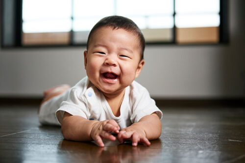 A baby smiling on floor.