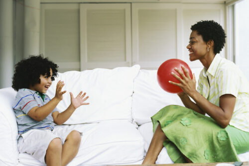 woman and boy on couch throwing ball